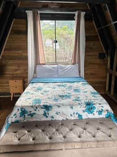 a bed in a room with a window at Chalé do Campo in Sumidouro