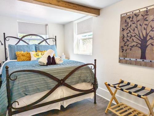 a bedroom with a bed with blue sheets and a tree painting at Peak View Guesthouse - Walk to Garden of the Gods - Hot Tub - Epic Views! in Colorado Springs