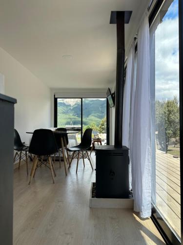 Una sala de estar con una mesa y sillas y una gran ventana. en Nina apart Meliquina, en San Martín de los Andes
