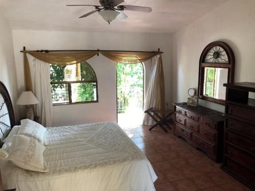Un dormitorio con una cama, una cómoda y ventanas. en Quinta Charito, Amplia Villa Familiar junto al Mar, en Los Cocos