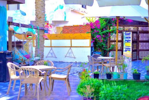 ダハブにあるcamp caesarの椅子とテーブルと傘のあるパティオ