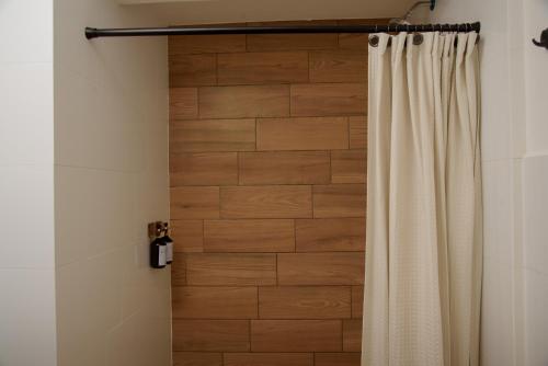 a shower curtain in a bathroom with a wooden wall at Glam - Apartamento exclusivo cerca del Consulado de México y centros comerciales in Quetzaltenango