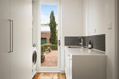 a kitchen with a sink and a door to a yard at Charming Red Brick Estate in Kew 5BR & Playhouse in Melbourne