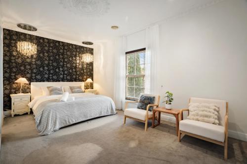 a bedroom with a large bed and two chairs at Charming Red Brick Estate in Kew 5BR & Playhouse in Melbourne