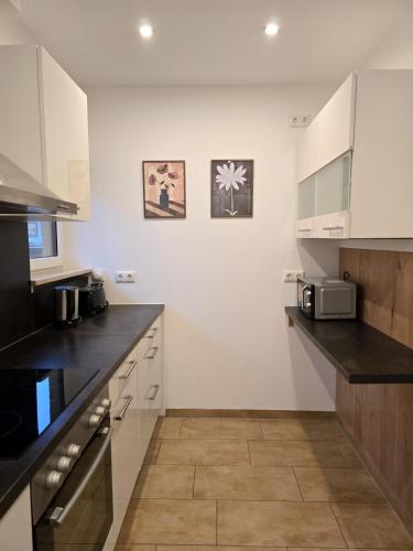 eine Küche mit weißen Schränken und schwarzen Arbeitsplatten in der Unterkunft Mountain Peak Apartment in Garmisch-Partenkirchen