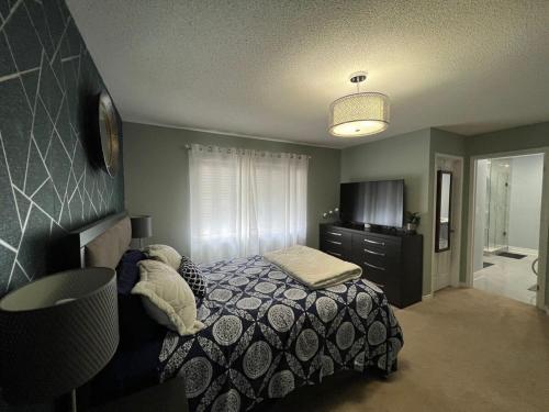 a bedroom with a bed and a dresser and a television at Luxury 5BR Home with Spa Bath in Burlington