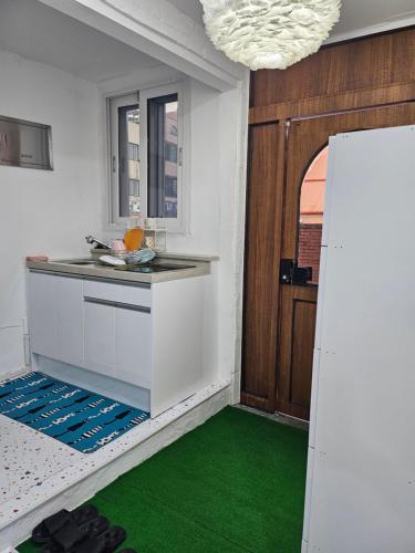 a kitchen with green flooring in a room with a refrigerator at 목포 달달마실 게스트하우스 in Mokpo