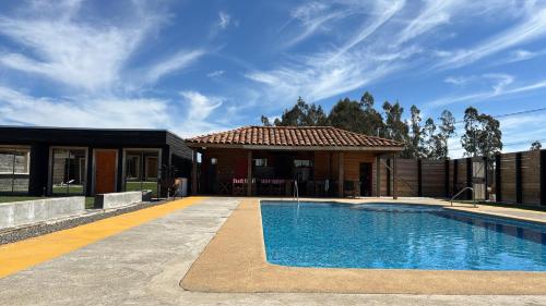 a house with a swimming pool in front of a house at Cabañas El Quincho de Putú in Constitución