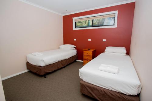 two beds in a room with a red wall at BIG4 Traralgon Park Lane Holiday Park in Traralgon