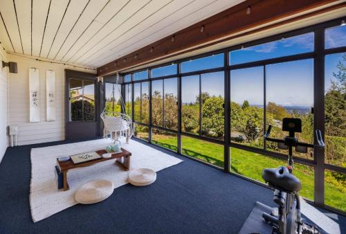 a living room with large windows and a table at Bellevue Somerset 2BR w Sunroom & Sweeping Views in Newcastle