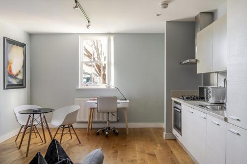 a kitchen with white cabinets and a table and chairs at Luxurious Private One Bedroom Apartment with Sky TV, Movies & Netflix in Braintree