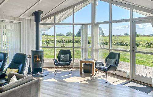 a living room with chairs and a fireplace with a view at Cozy Home In Rudkøbing With Sauna in Spodsbjerg