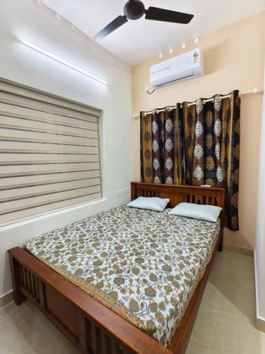 a bedroom with a bed and a window with a fan at Urban villa in Trivandrum