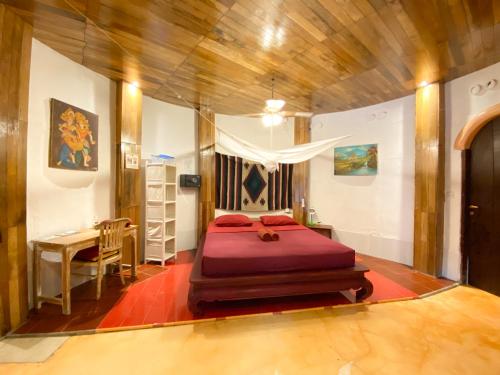 a bedroom with a bed and a desk in it at Serenity Eco Guesthouse and Yoga- CHSE certified in Canggu