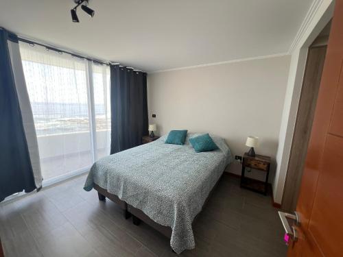 a bedroom with a bed and a large window at Departamento frente a la playa in Iquique