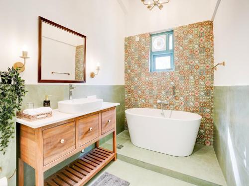 Valencia By DanCenter - 3 Bhk Villa in Siolim في Camorlim: حمام مزود بحوض استحمام ومغسلة ومرآة