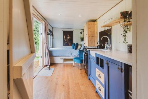 eine Küche mit blauen Schränken und einem Bett im Hintergrund in der Unterkunft The Hideaway at Hidden Wood Glamping in Corsley