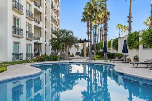 a swimming pool in the courtyard of a building with palm trees at Beautiful Apartment a few of minutes to the Beach in Cabo San Lucas