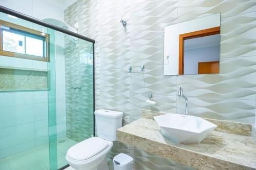 a bathroom with a sink and a toilet and a mirror at K&S Kanto Sereno in Pirenópolis