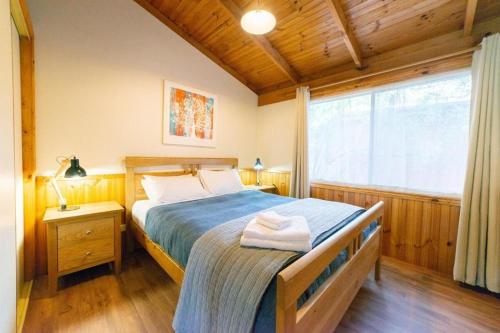 a bedroom with a bed and a large window at Awonga Cottages in Halls Gap