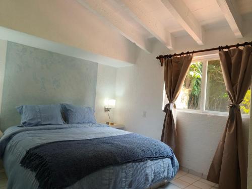 a bedroom with a bed and a window at Portal Azahualco Bungalow close to the mountain in Tepoztlán