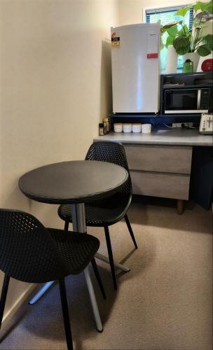 a table and two chairs next to a counter with a refrigerator at Christchurch Airport House in Christchurch