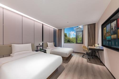 una habitación de hotel con dos camas y un televisor de pantalla plana en Urna Hotel Xiamen Railway Station Lianhua Road Subway Station Branch, en Xiamen