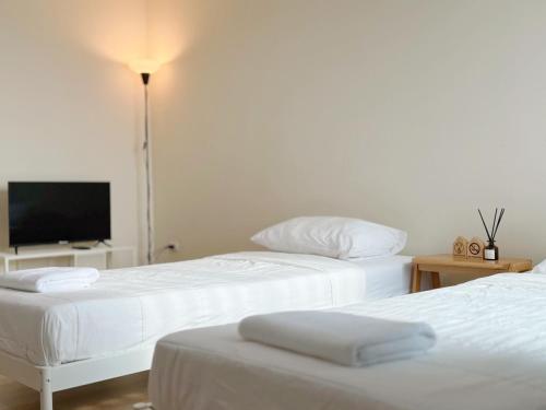 two white beds in a room with a flat screen tv at Jira Simply room Suvarnabhumi Airport 15 mins in Lat Krabang