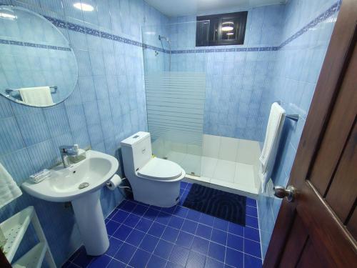 a blue tiled bathroom with a toilet and a sink at Comfortable and quiet double room in Santo Domingo