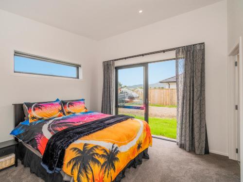 a bedroom with a bed and a large window at Sun and Sea Sanctuary - Whitianga Holiday Home in Whitianga