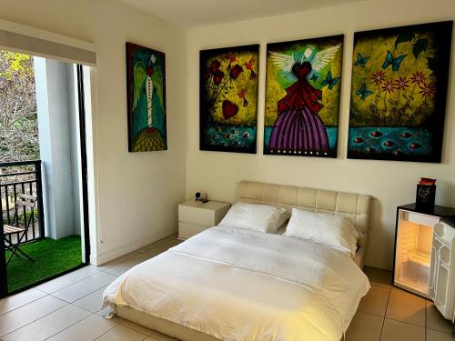 a bedroom with a bed with four paintings on the wall at The Art House Little Havana in Miami