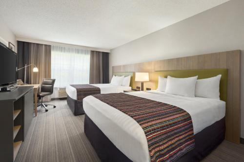 a hotel room with two beds and a desk at Country Inn & Suites by Radisson, Decorah, IA in Decorah