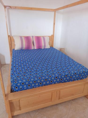 a wooden bed with a blue cover on it at Residence wa maore in Mahajanga