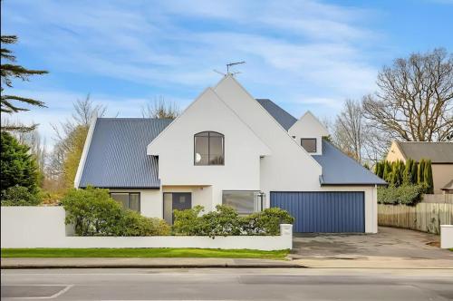a white house with a blue roof at Christchurch Airport House in Christchurch
