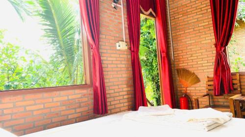 a bed in a room with red curtains and a window at Nhà Nghỉ Vượn Hót in Tân Phú