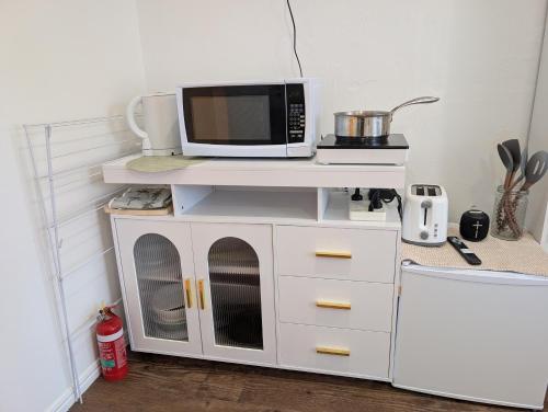 a microwave sitting on top of a white cabinet at Peaceful, Walk to Beach, Bikes, AC, Starlink in Byron Bay