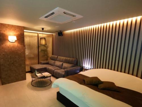 ein Hotelzimmer mit einem Bett und einer Couch in der Unterkunft HOTEL felice Osaka Itami Airport - Vacation STAY 53128v in Toyonaka