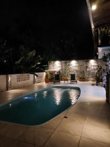 una piscina notturna con sedie e luci di Loft das Flores a Pomerode