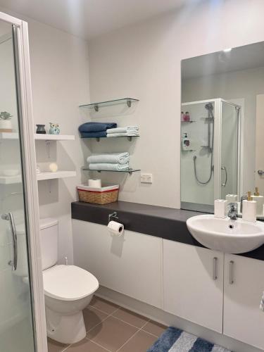 a white bathroom with a toilet and a sink at Convenient & Comfortable Apartment Suite in Albany in Auckland