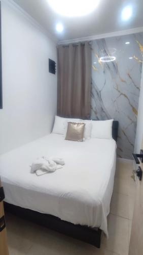 a bedroom with a bed with white sheets and a window at Jazmin's Apartments in Oranjestad