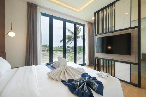 Bellevue Villa Canggu في Pererenan: غرفة نوم بسرير أبيض مع تلفزيون ونافذة كبيرة