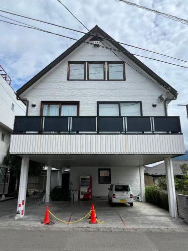 Una casa blanca con un coche aparcado delante. en 富士の屋河口湖, en Fujikawaguchiko