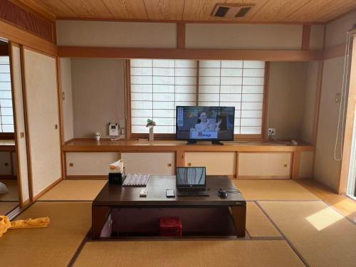 Habitación con escritorio, ordenador portátil y TV. en 富士の屋河口湖, en Fujikawaguchiko