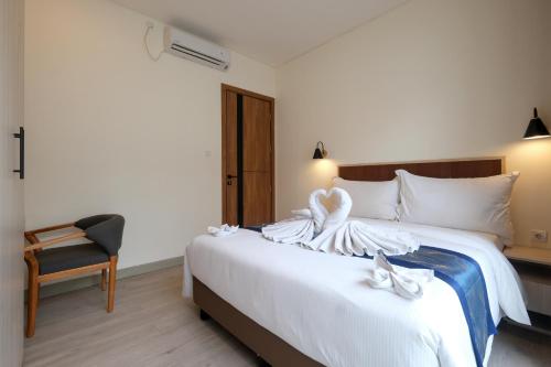 a bedroom with a bed with white sheets and a chair at Bellevue Villa Canggu in Canggu