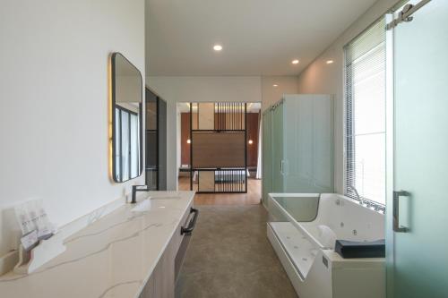 Bellevue Villa Canggu في Pererenan: حمام به مغسلتين وحوض استحمام ومرآة