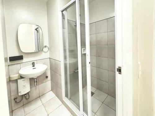een witte badkamer met een wastafel en een douche bij Sweethome in Manilla
