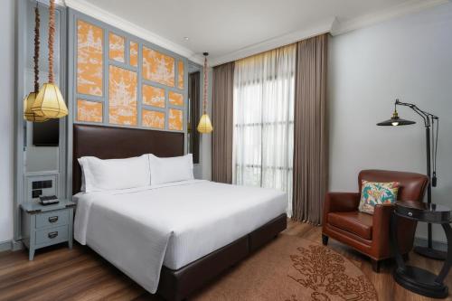 a bedroom with a white bed and a chair at Metropole, Bangkok, a Tribute Portfolio Hotel in Bangkok