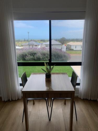 a table and chairs in front of a large window at Charming 1-bed Coastal Escape at Links Lady Bay in Normanville