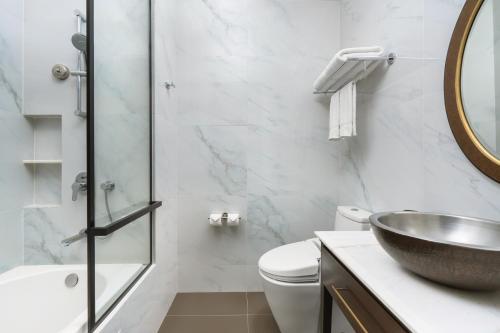 a bathroom with a sink and a toilet and a mirror at Metropole, Bangkok, a Tribute Portfolio Hotel in Bangkok