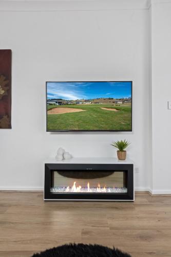 a living room with a fireplace with a tv above it at Charming 1-bed Coastal Escape at Links Lady Bay in Normanville